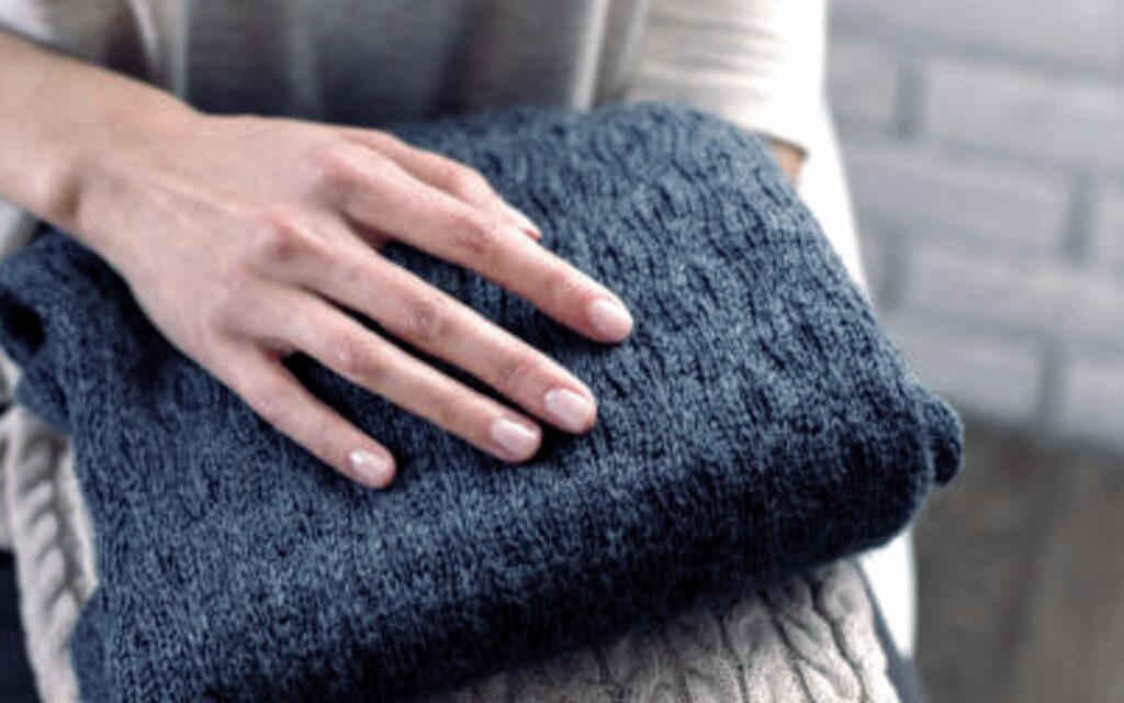 Kobieca dłoń dotyka ubrania z wełny