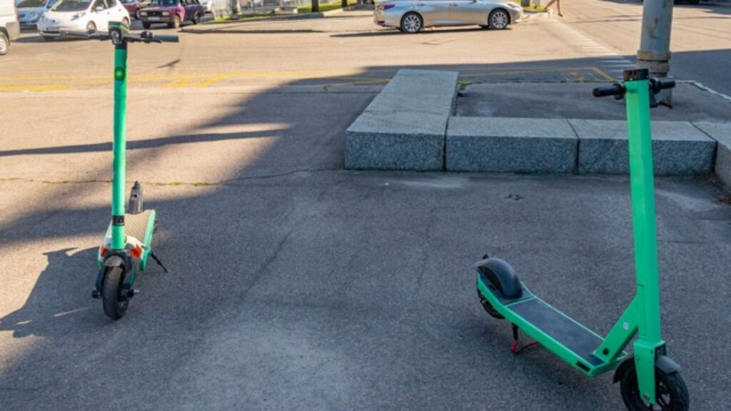 Chodnik, dwie hulajnogi stoją chaotycznie, ewidentnie tam, gdzie stać nie powinny.