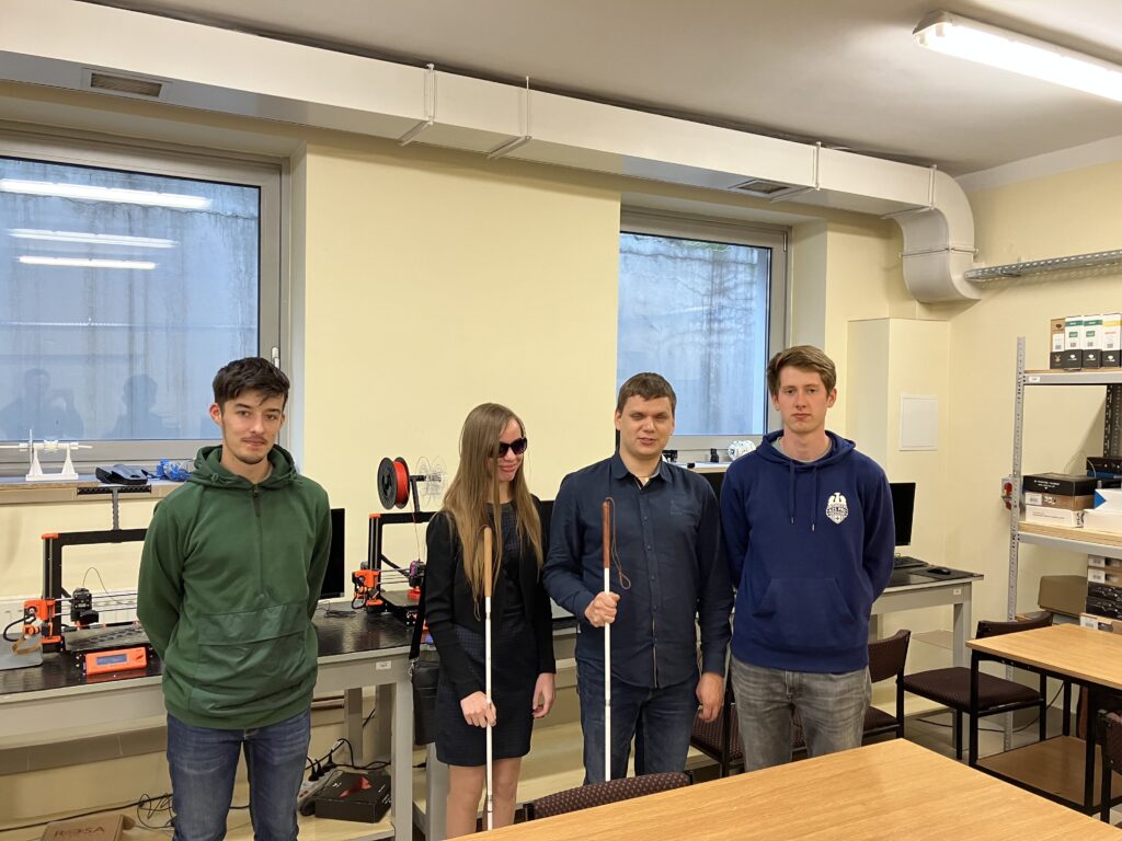 Dawid i Monika stoją w sali w towarzystwie dwóch młodych ludzi. Za nimi widać kilka stanowisk z komputerami i drukarkami 3d. Na parapetach okien ułożone są wydruki.