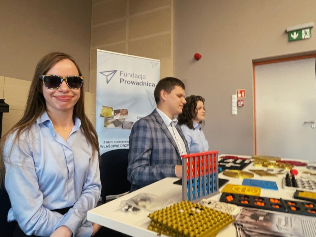 Monika, Julita i Dawid przy stanowisku z wydrukami.